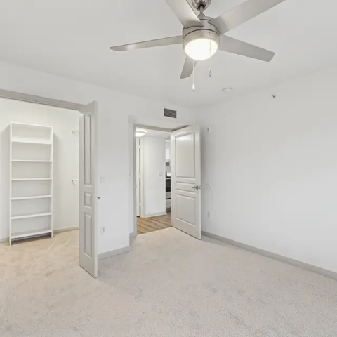 A room with a ceiling fan and a carpeted floor.